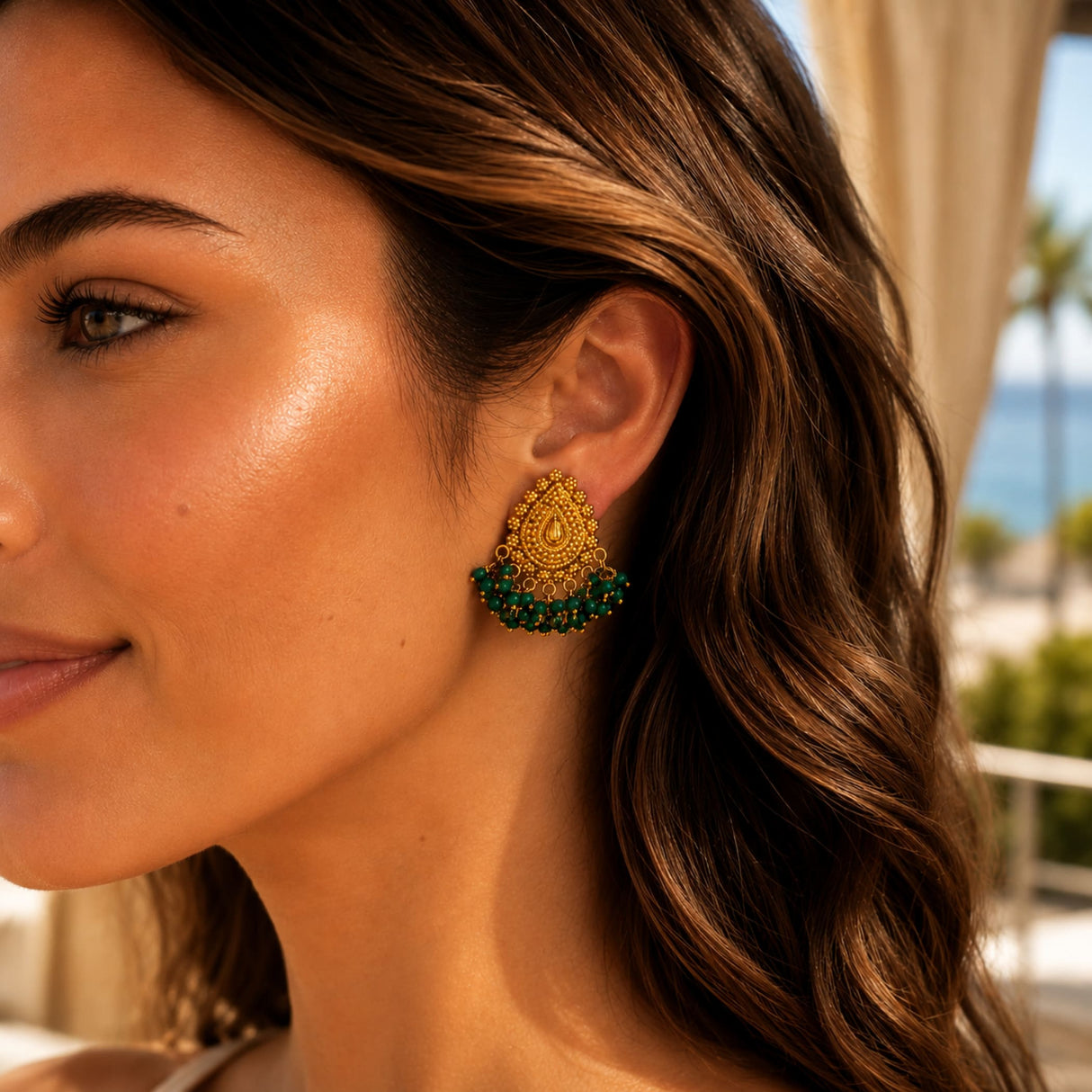 Indian chandbali gold tone dangle earrings with intricate filigree teardrop and cascading emerald green bead fringe