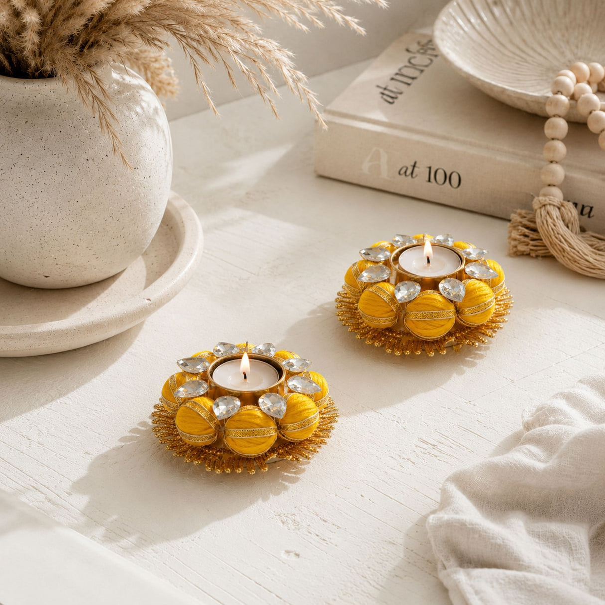 Yellow fabric-covered tea light holders with clear crystal embellishments and gold-toned metal for indian festive decor