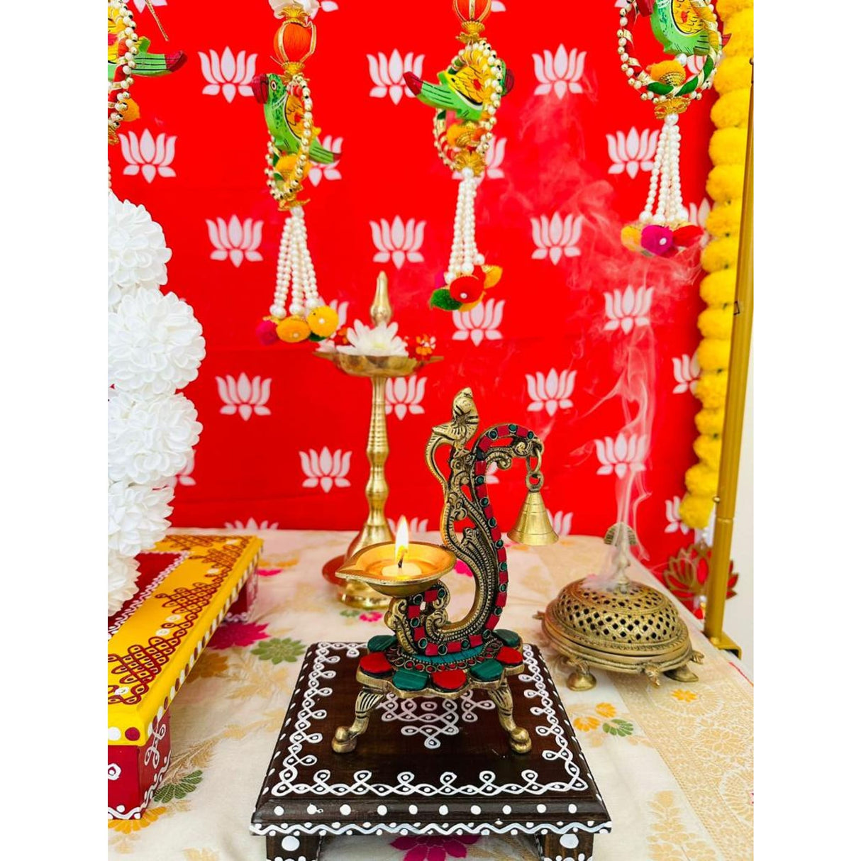 Ornate brass peacock-shaped oil lamp with burning wick for Indian wedding and festival decor