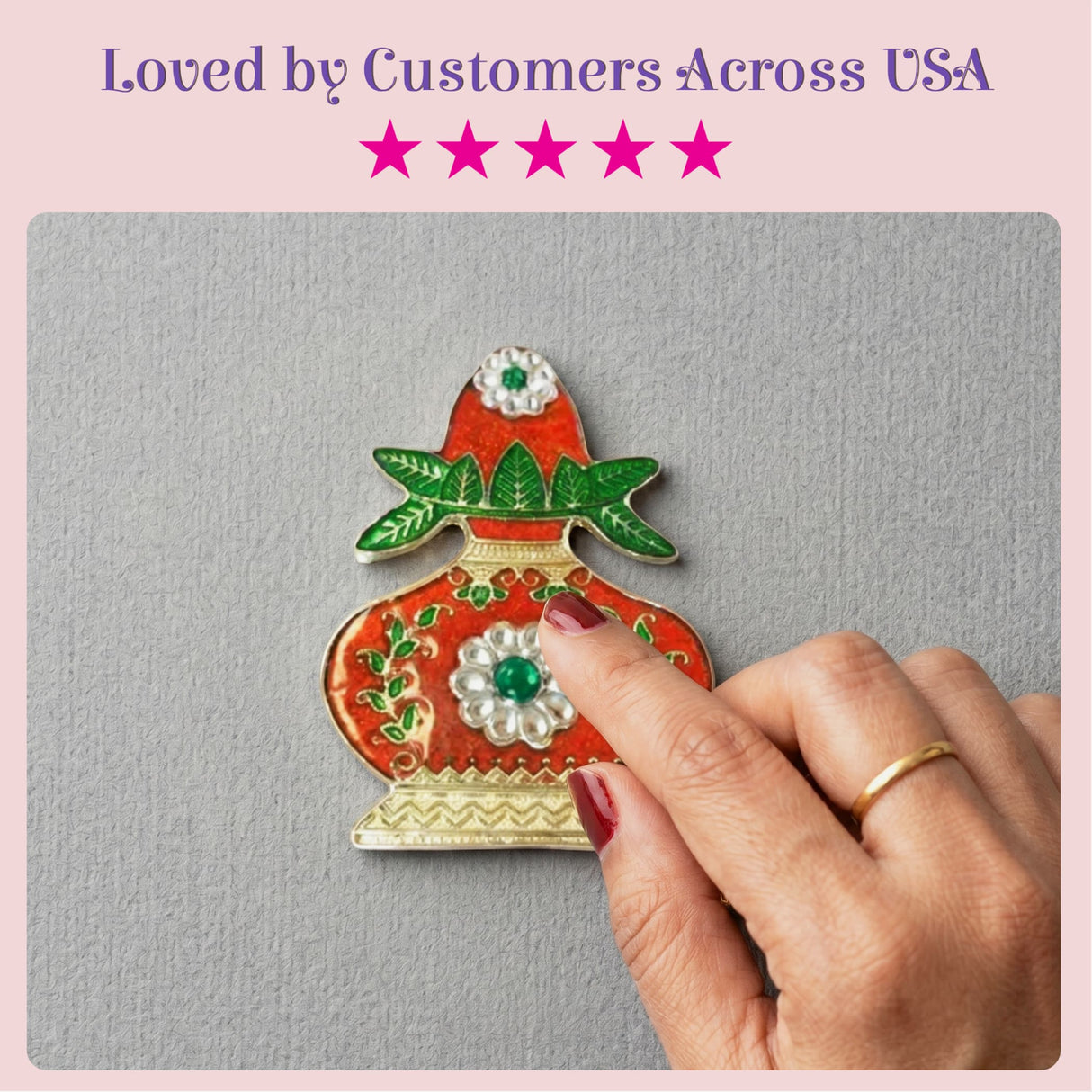 A vibrant red enamel kalash haldi kumkum holder with green leafy details and emerald stones in a gold-toned frame