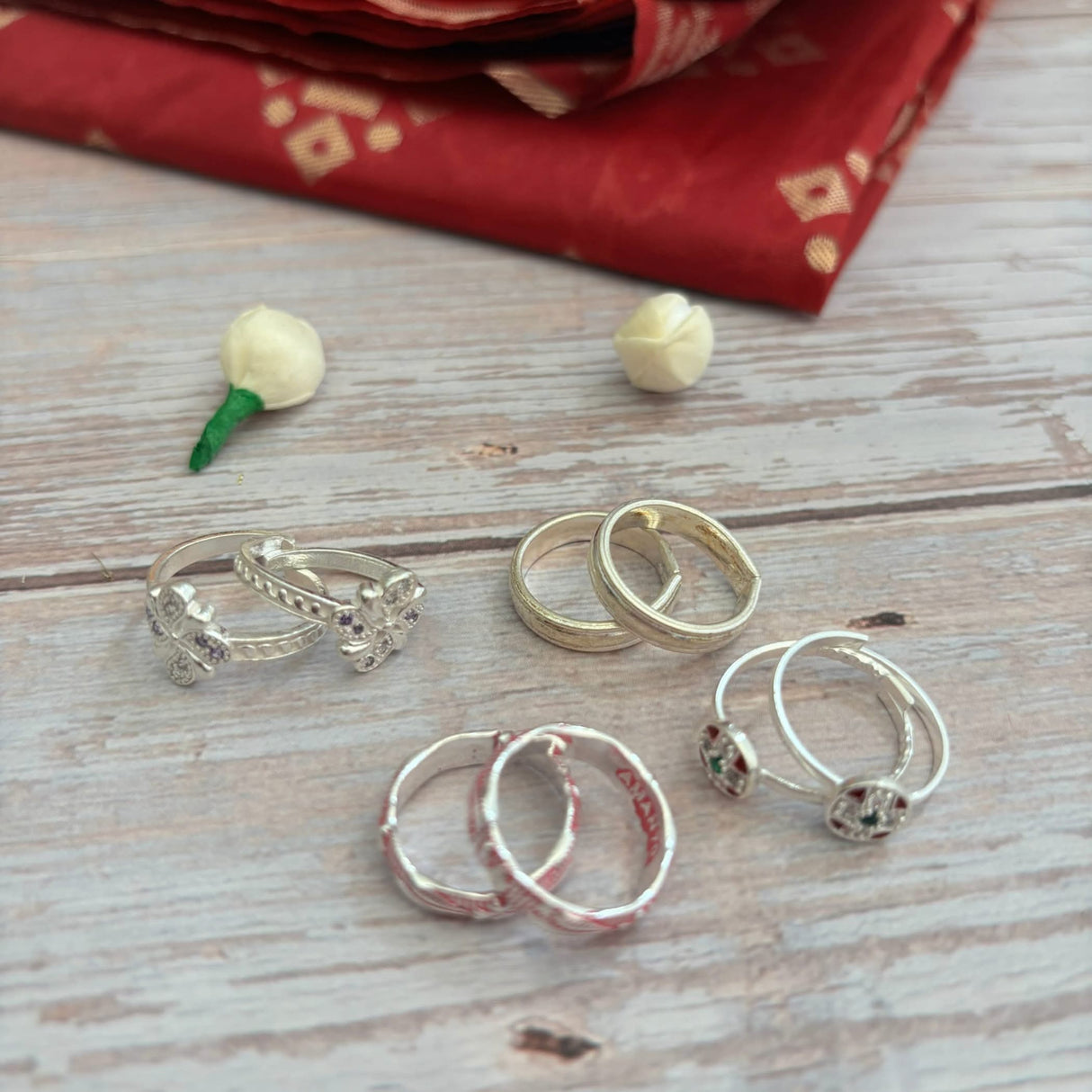 Assorted sterling silver toe rings displayed with traditional jewelry and accessories