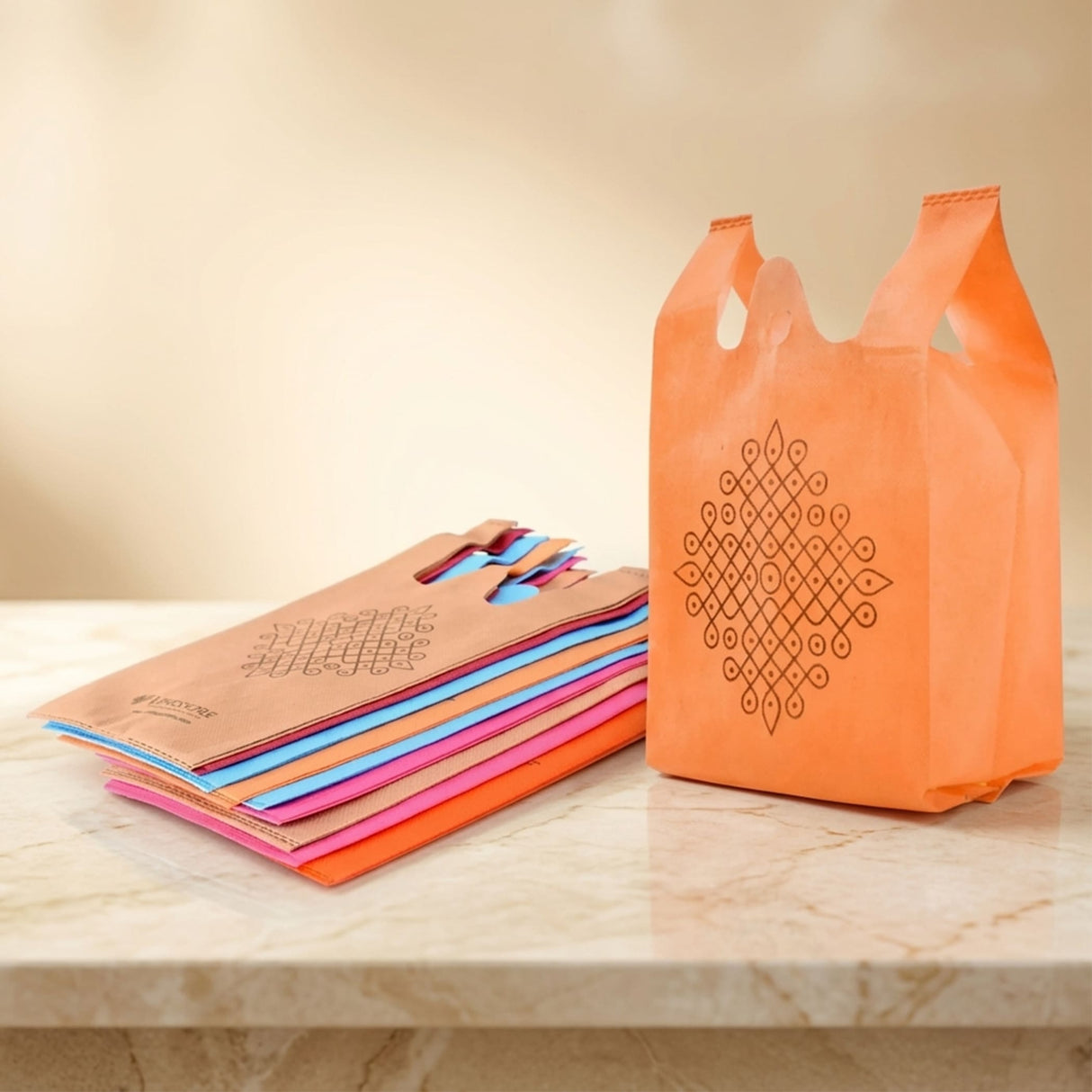 Orange reusable non woven shopping bag with black geometric kolam print for indian wedding favors and puja events