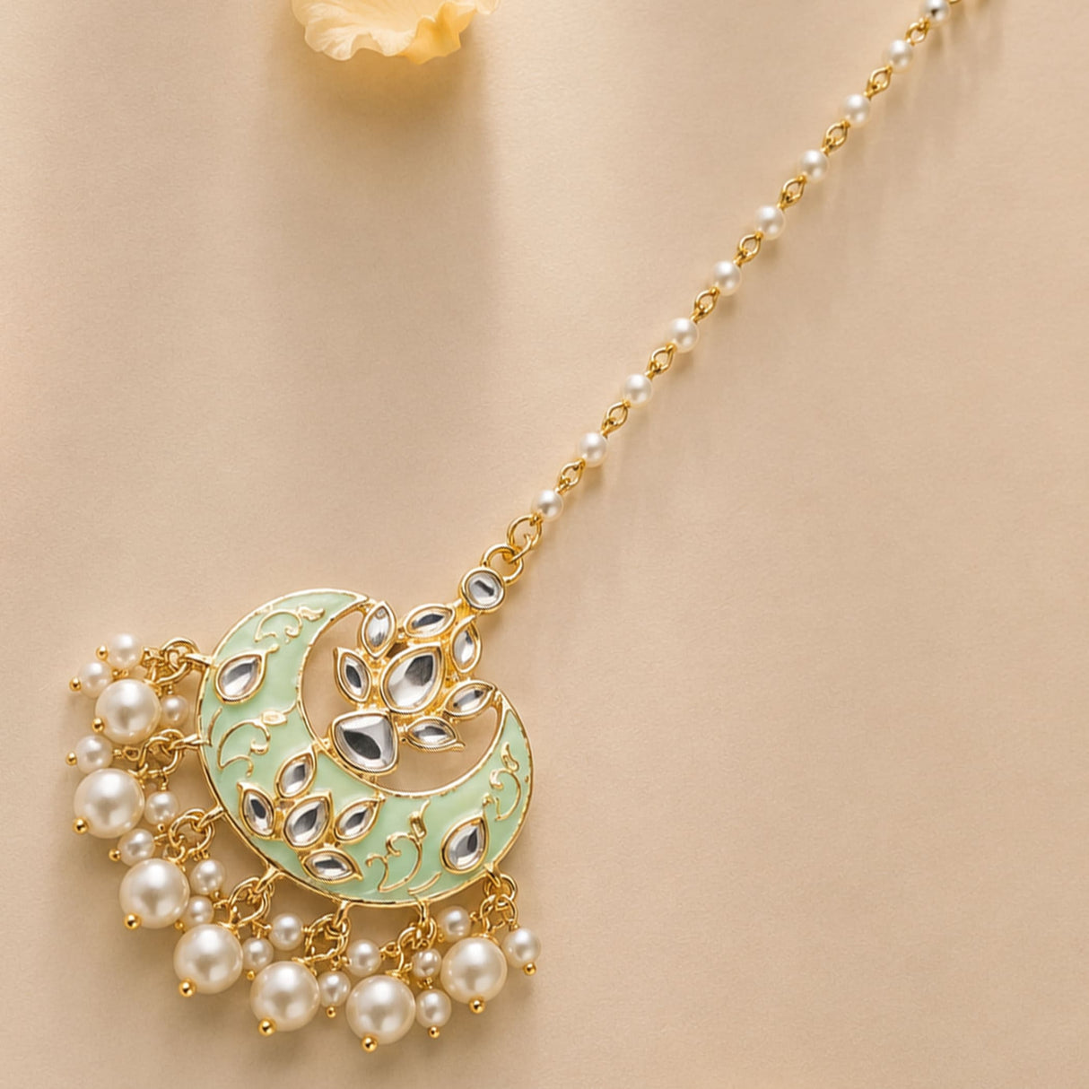 Kundan chand maang tikka with gold plating in mint green and gold featuring sparkling stones and dangling pearls for weddings