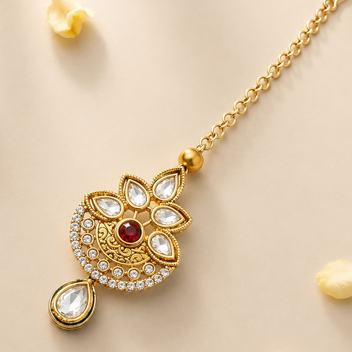 Gold-plated kundan work maang tikka with red central gemstone and clear teardrop stones for Indian wedding jewelry