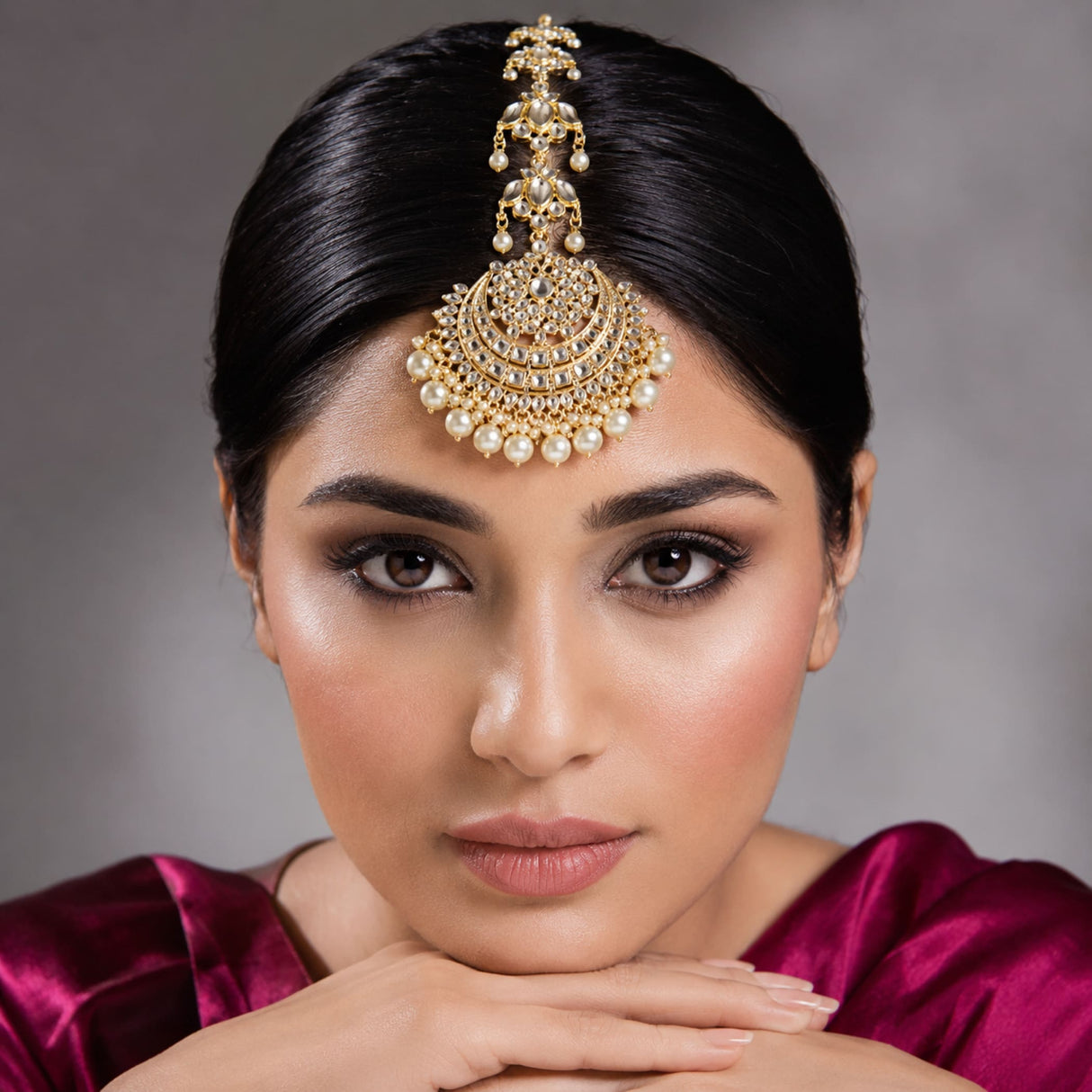 Gold-colored Indian maang tikka with kundan work featuring intricate diamond and pearl embellishments for bridal wear