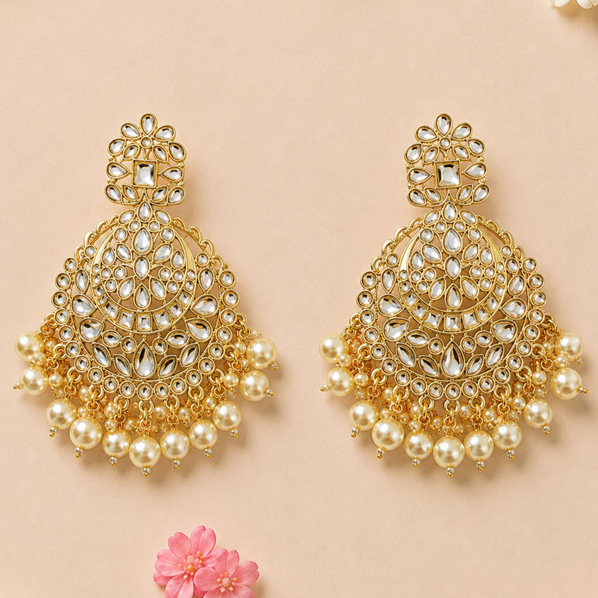 Gold tone oversized Indian kundan chandelier earrings with intricate metalwork and faux pearl dangles for ethnic wear