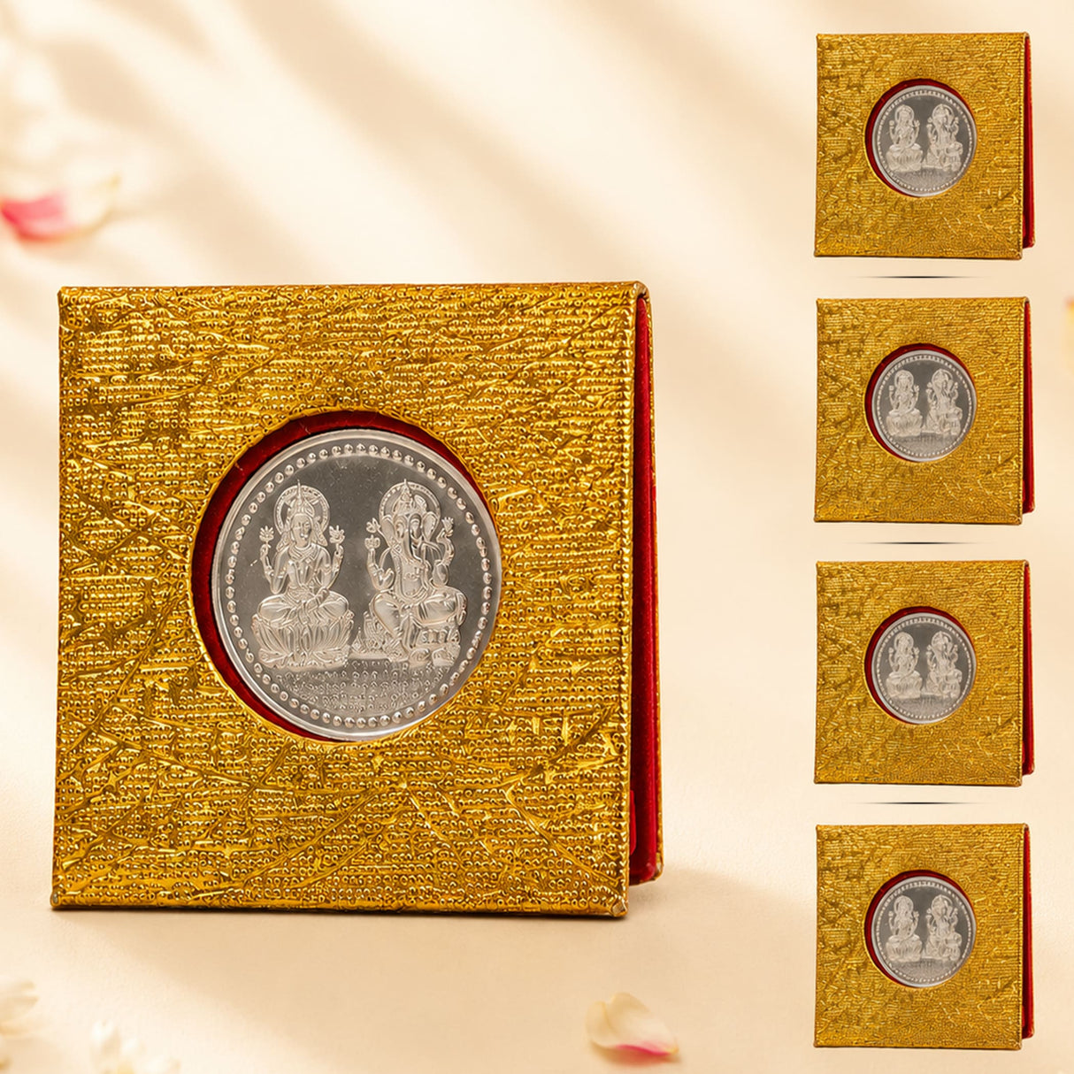 Gold-colored textured box containing a silver-plated laxmi ganesh coin with intricate deity depictions for diwali gift