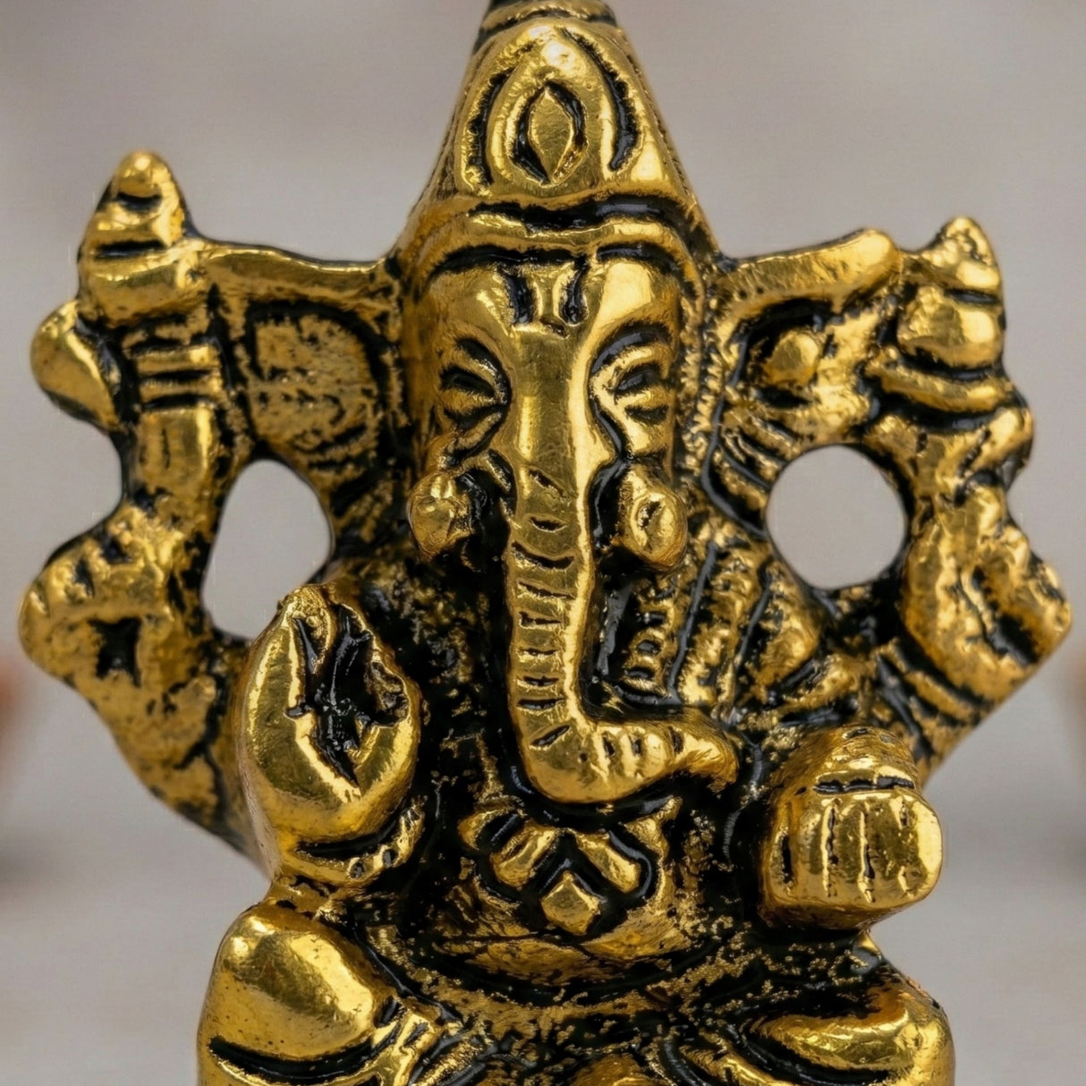 Golden metallic Lord Ganesha car idol with intricate details and black accents