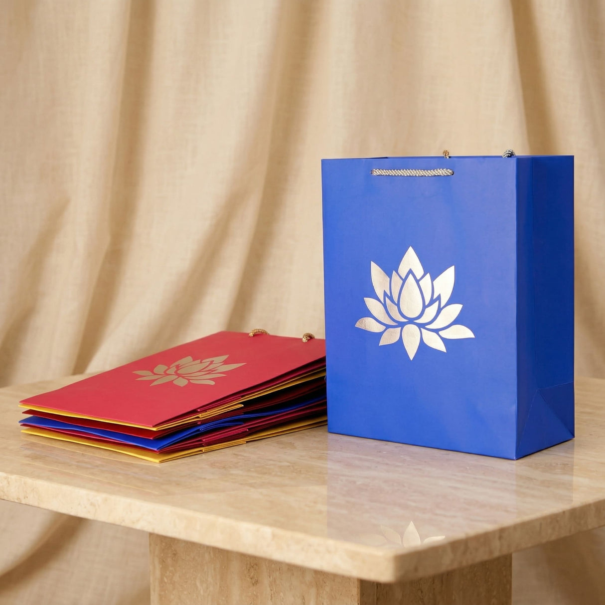 Blue paper shopping bag with white lotus emblem and metallic handles for indian wedding and diwali gifts