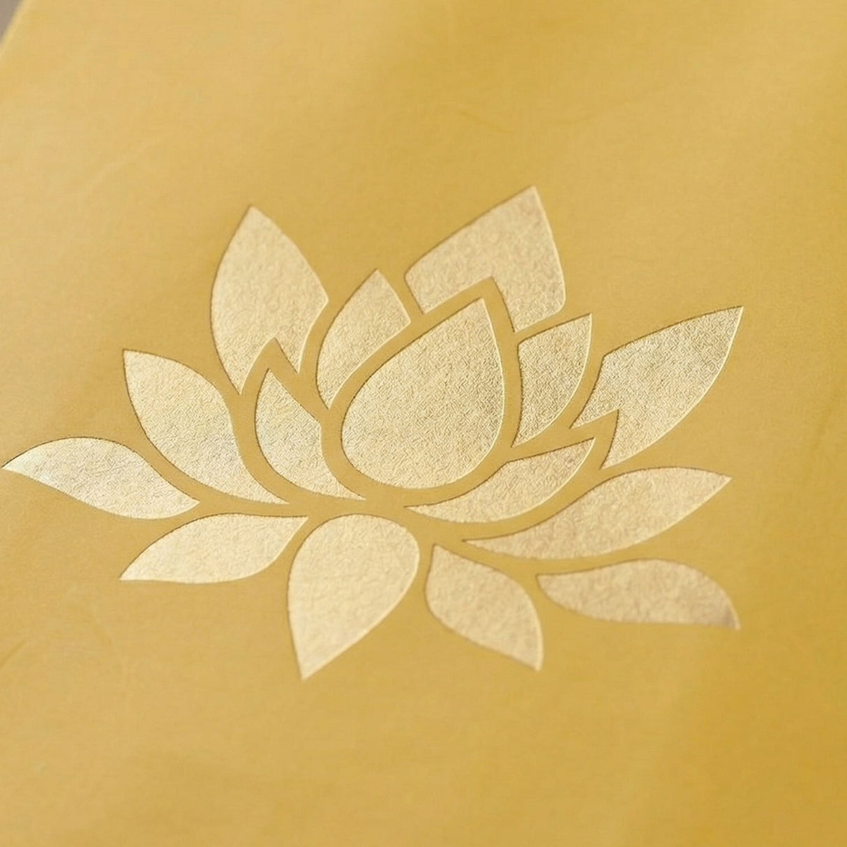 Lotus paper carry bag with delicate gold foil lotus flower embossed on soft yellow textured surface for gift giving
