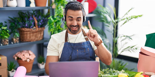 Man in an apron and headset using a laptop.