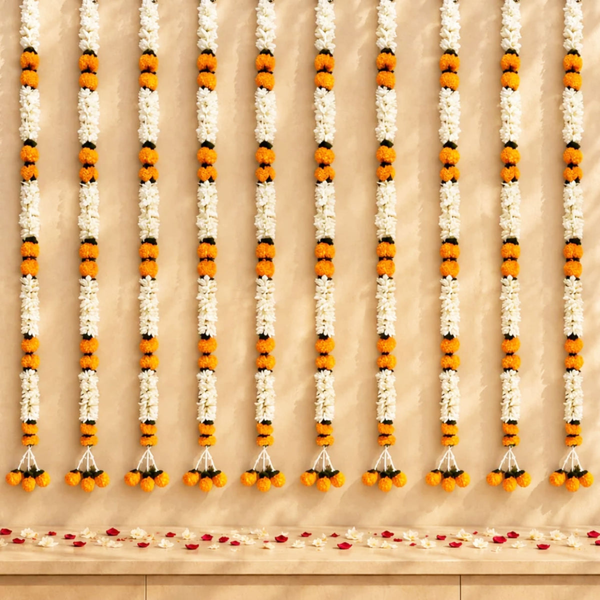 Artificial jasmine and marigold flower garlands in vibrant orange and white with black accents for wedding and festive decor
