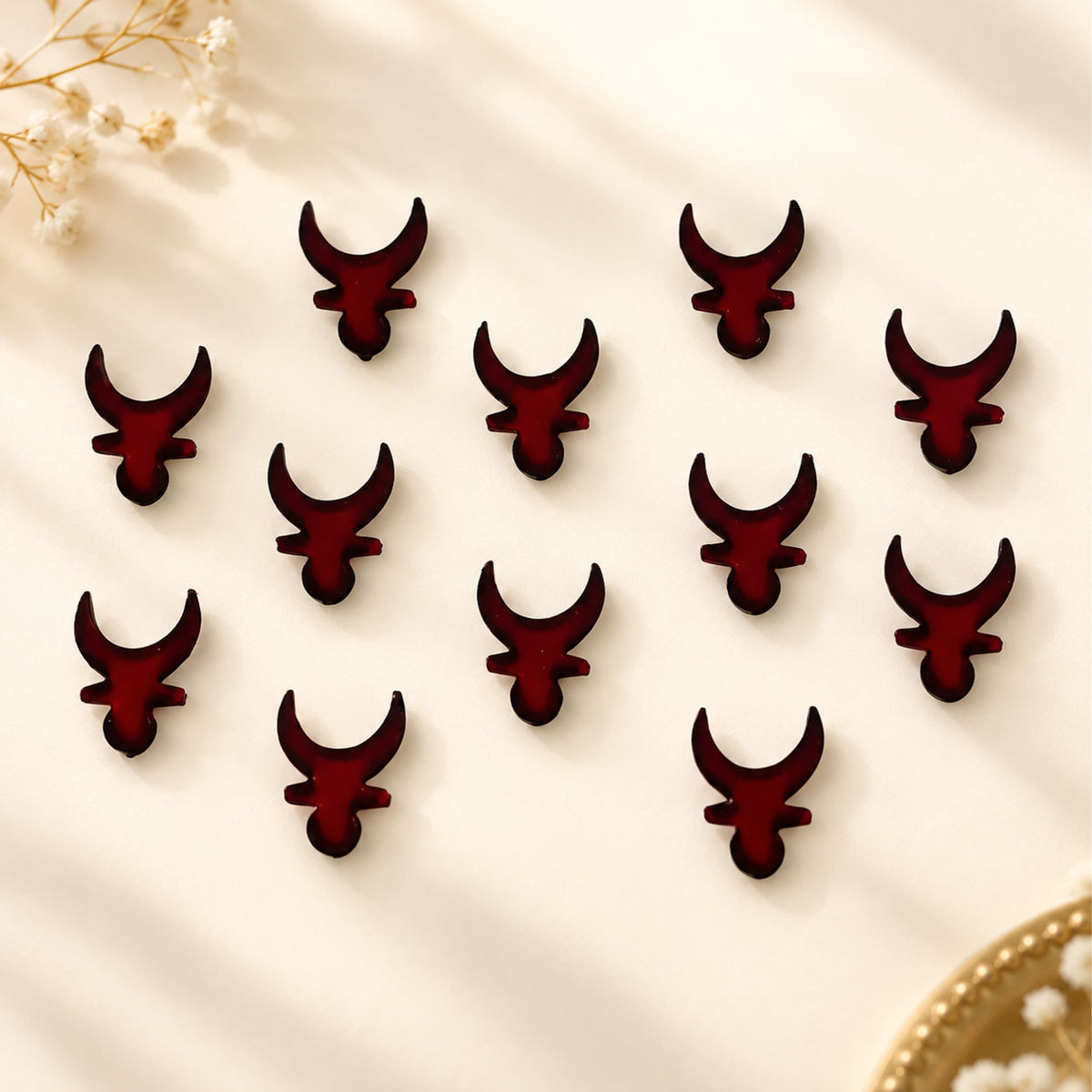 Dark red glossy resin bull head clips arranged in a pattern from indian marathi bindi booklets collection for traditional use