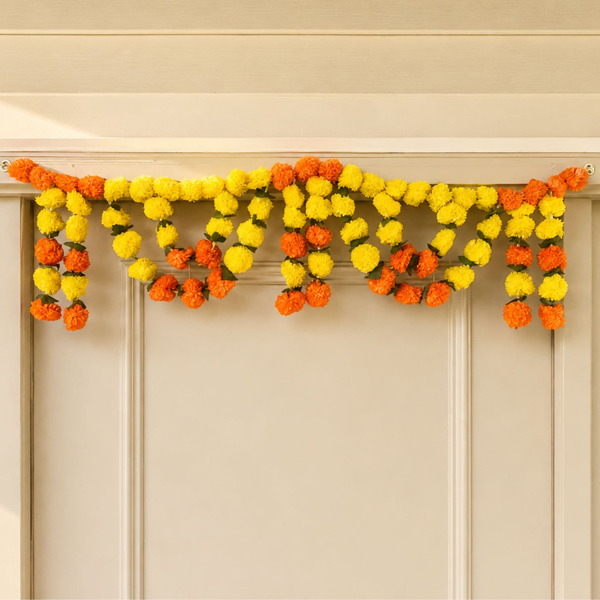 A vibrant orange and yellow artificial marigold mango leaf door toran garland for puja diwali and festive decor
