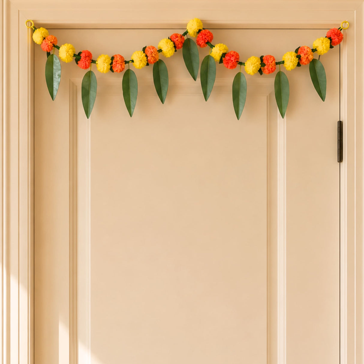 A festive marigold mango leaf door toran hanging valance with yellow and orange flowers and green leaves for indoor outdoor decor