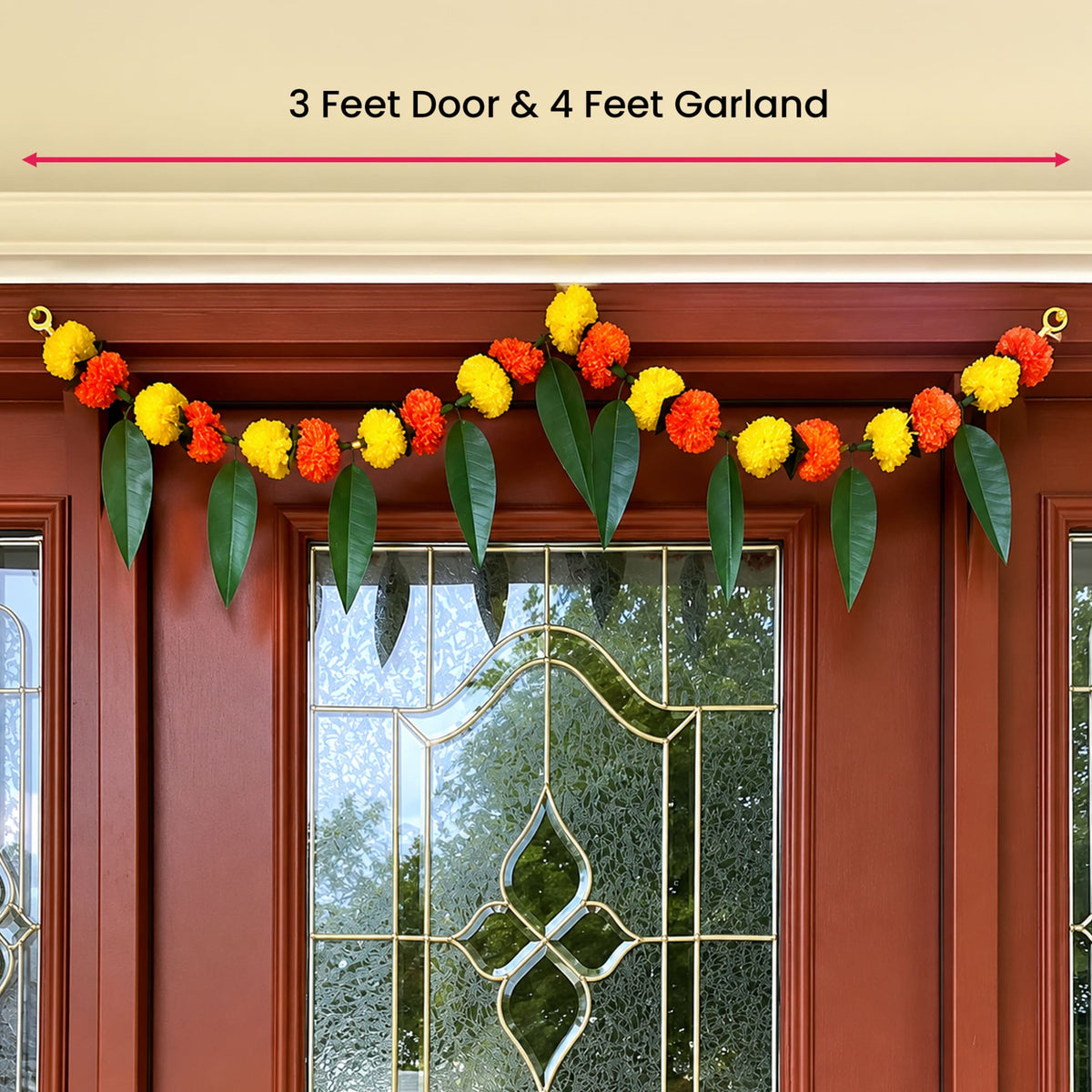 A vibrant orange and yellow artificial marigold flower and mango leaf garland on a red door for festive decor