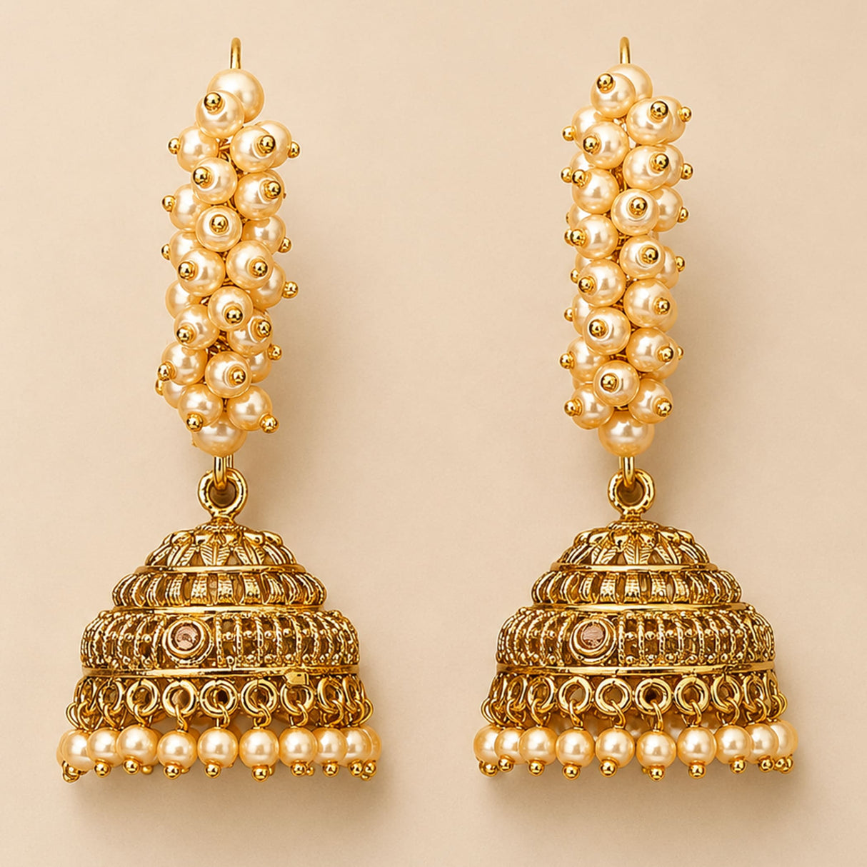 Golden jhumka earrings with cream pearl strands and intricate metalwork in gold tone for diwali and ethnic wear
