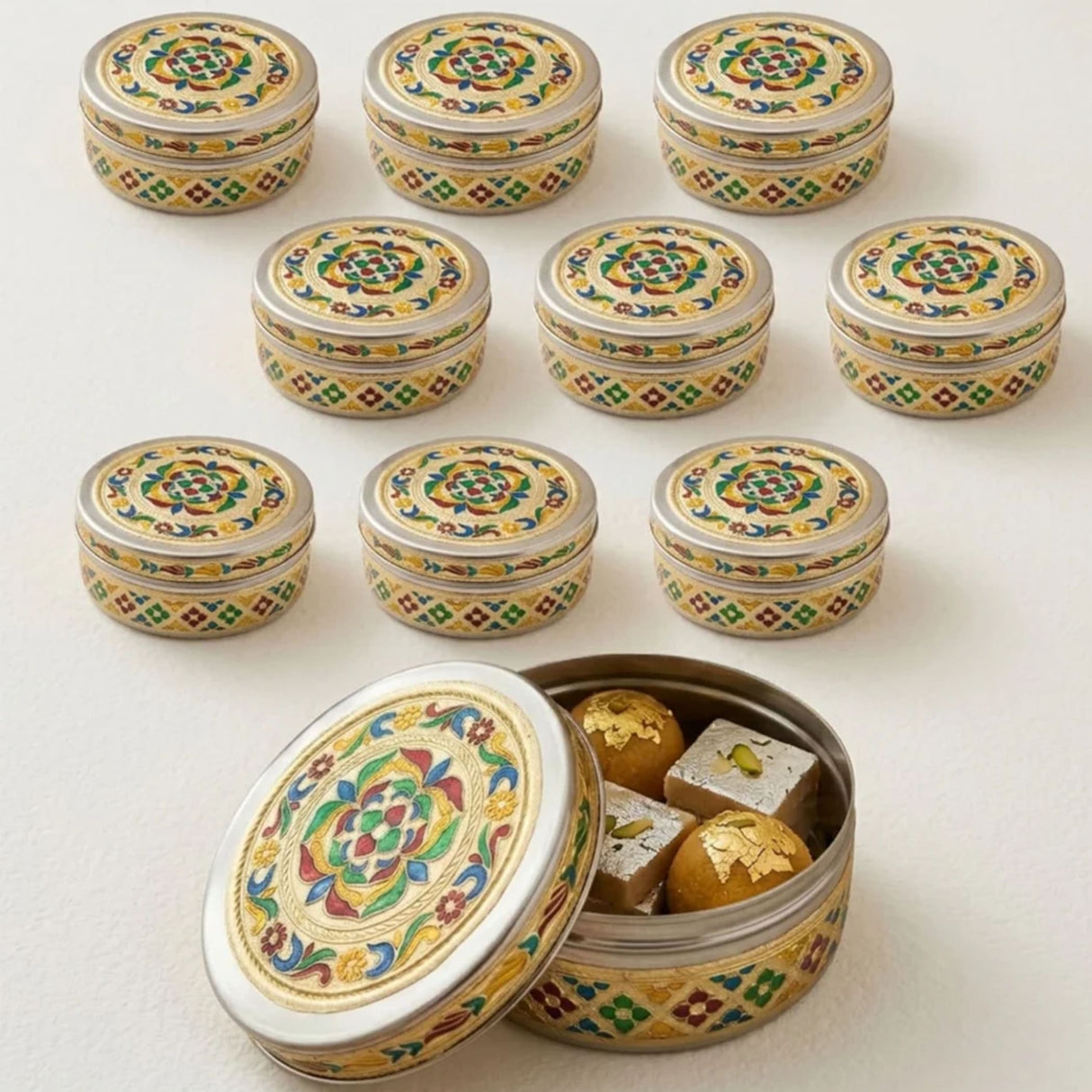 Silver-colored meenakari stainless steel round cookie tin with colorful floral and geometric enamel designs for sweets storage