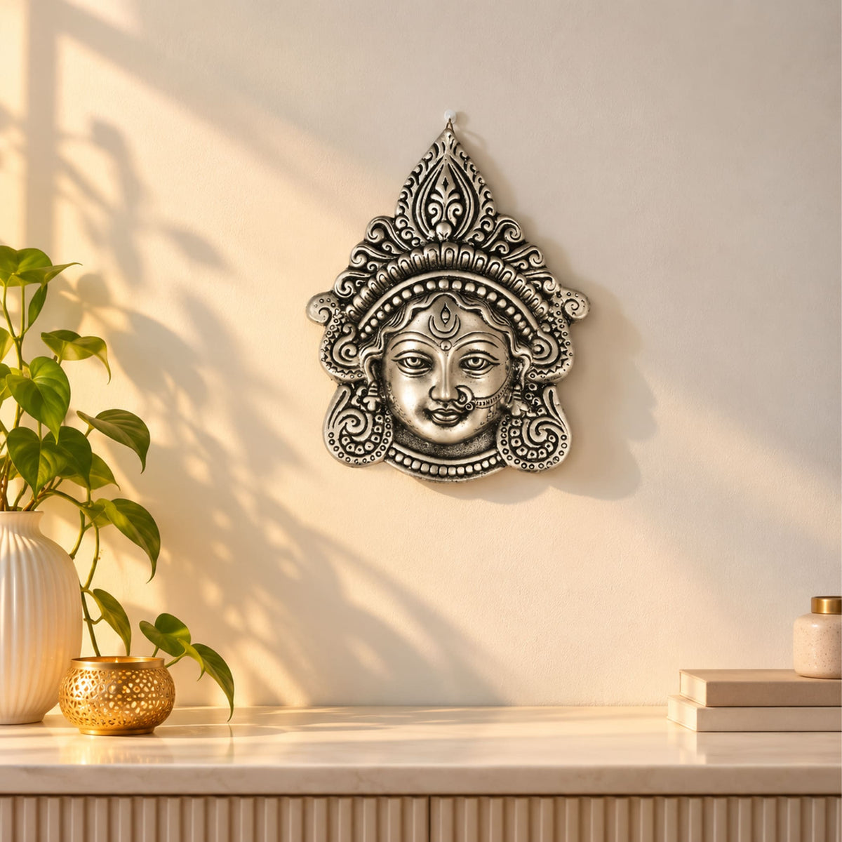 Silver-toned metal durga face wall hanging with intricate headpiece and jewelry for home decor and puja use