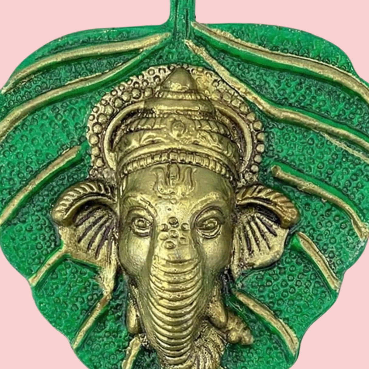 Golden Ganesha pendant on vibrant green leaf background, Diwali decor