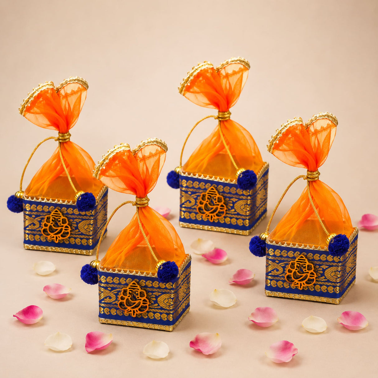 Pack of 4 blue and gold ornate small potli gift boxes with orange sheer organza bags and blue pom-poms for Indian festivals