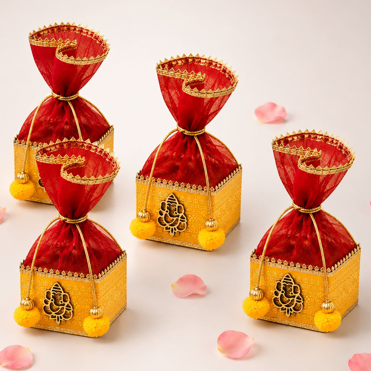 Pack of 4 red sheer organza drawstring potli bags with gold trim and yellow pom-poms in embossed ganesha golden boxes for gifts