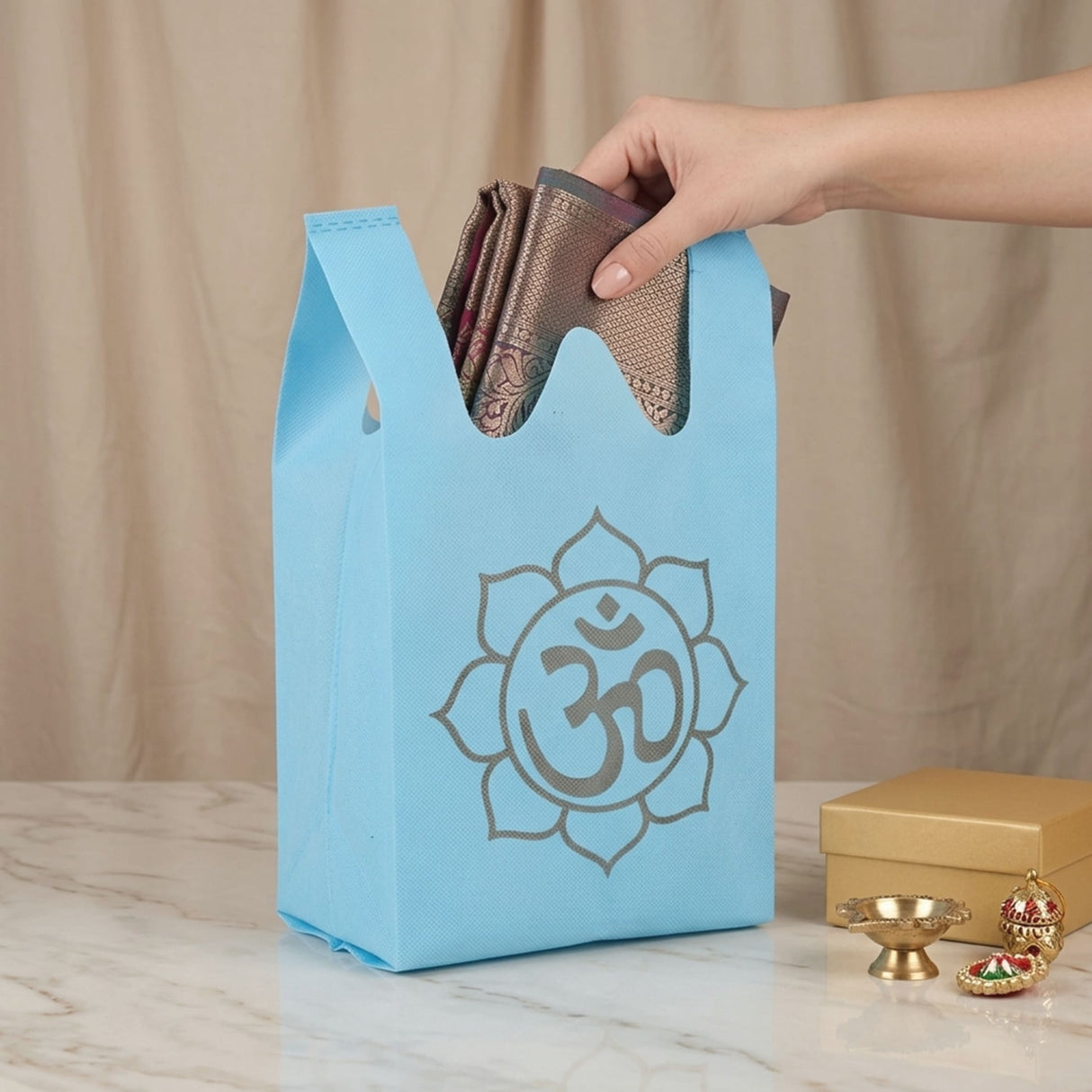 Light blue reusable non woven tote bag with gray om symbol for Indian wedding housewarming puja gifts and favors