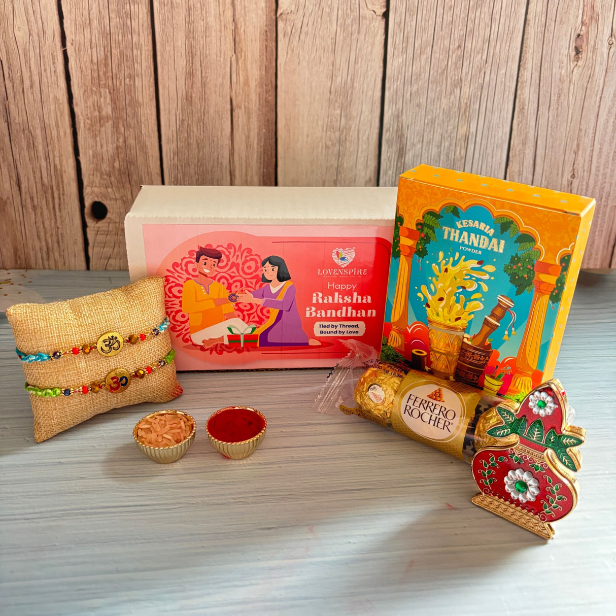 Religious Om Rakhi Hamper for Brother - Includes 2 Colorful Adjustable Bracelet Threads, Chocolate, Haldi Kumkum Holder, Thandai, Roli Chawal & Gift Box