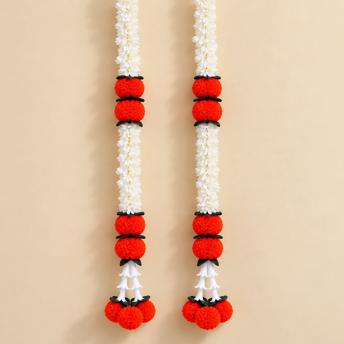 Two artificial jasmine marigold garlands featuring white flowers red pom-poms and black connectors for festive décor