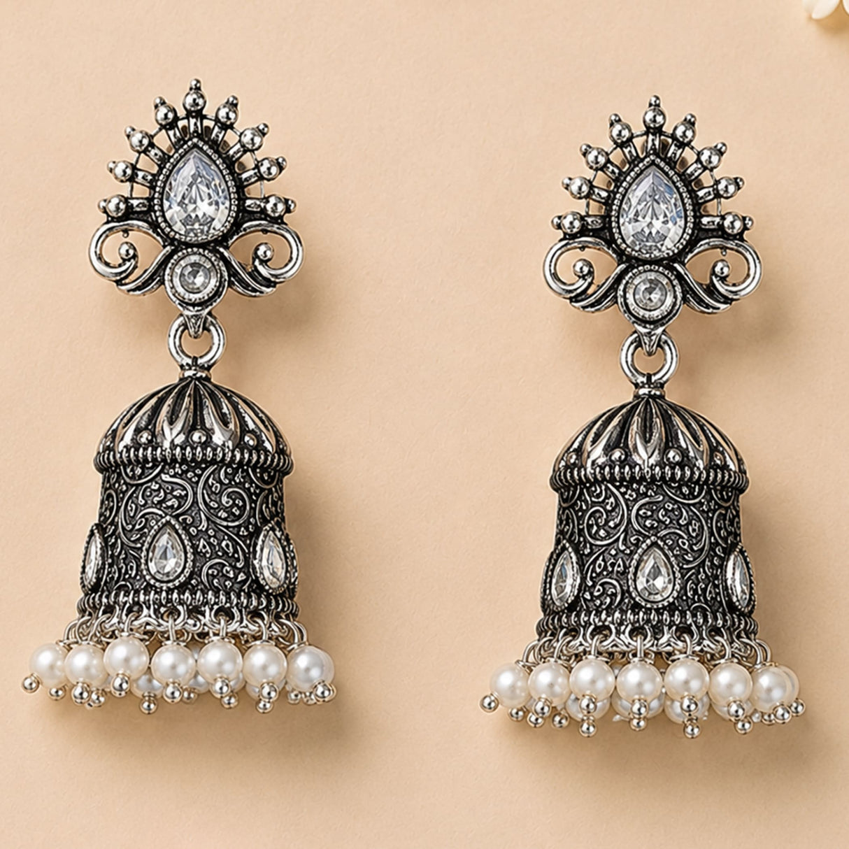 Indian oxidized silver jhumka earrings with intricate filigree, teardrop crystal, and dangling faux pearls for ethnic wear