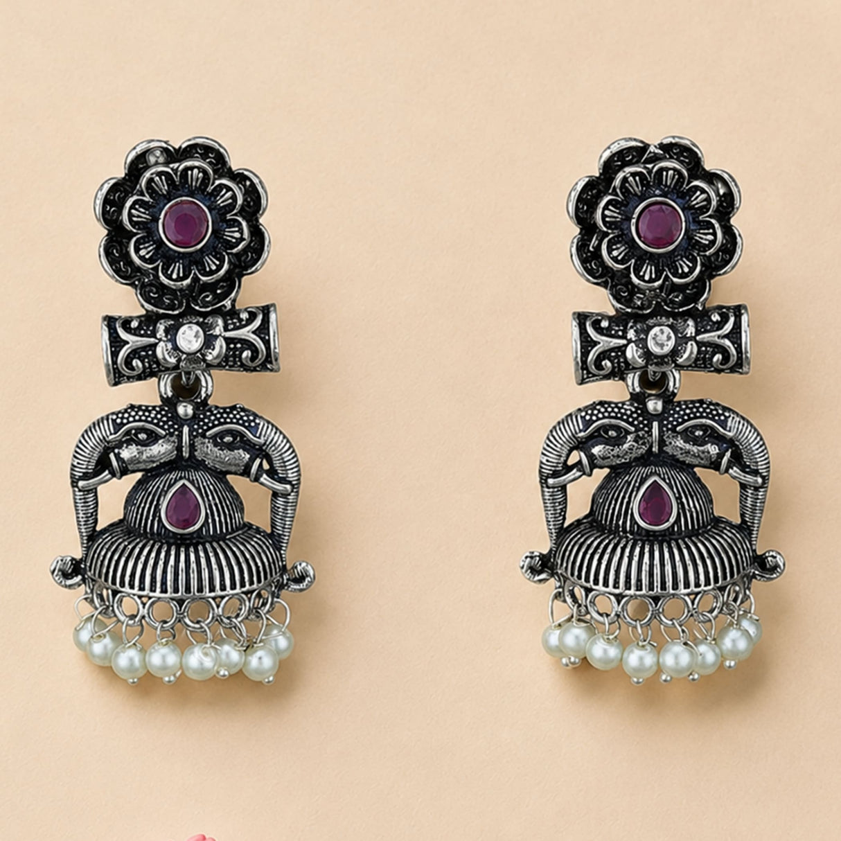 Silver oxidized floral jhumka earrings with intricate elephant designs purple gemstones and faux pearl dangles for festive wear