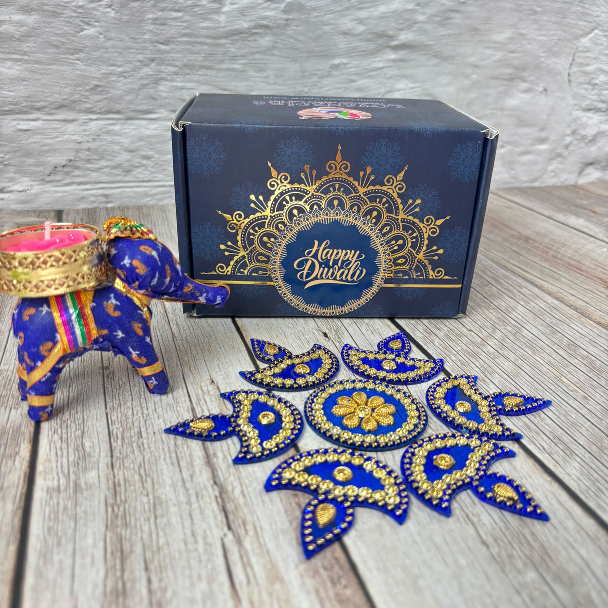 Blue elephant figurine with pink candle, gold decor, and Happy Diwali gift box