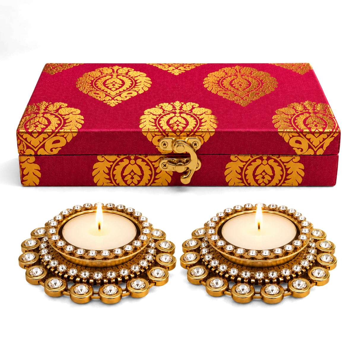 Red and gold patterned fabric box with golden clasp and two ornate gold diya holders with clear crystals for diwali gifts