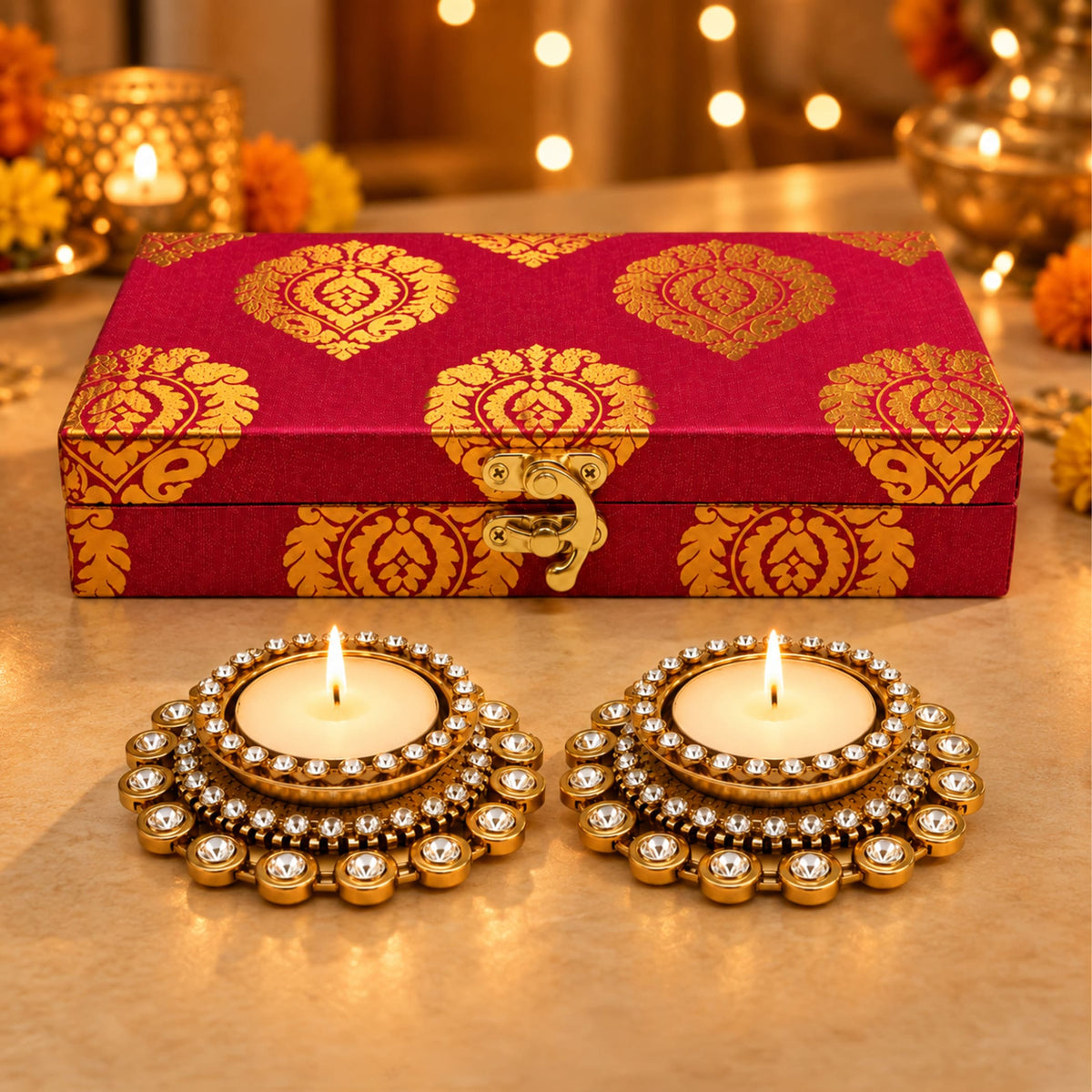 Personalized red and gold patterned gift box with decorative clasp behind ornate golden candle holders for diwali decor
