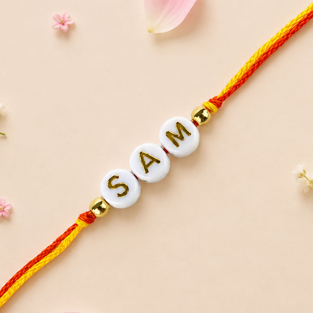 Designer custom named rakhi with white beads gold lettering on red yellow braided cord for brother and bhabhi protection gift