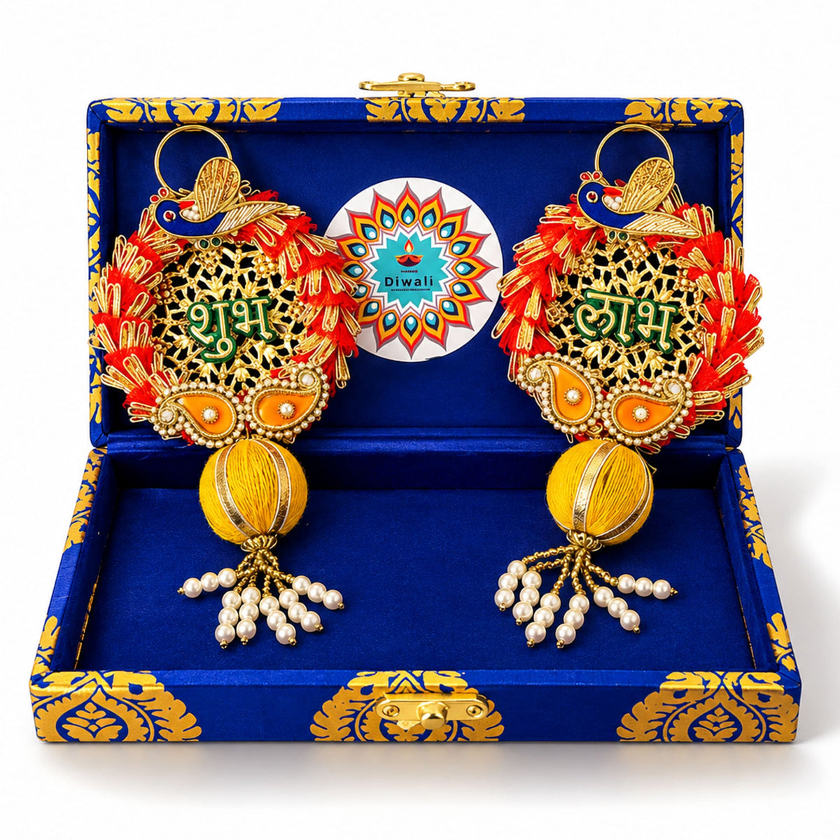 A pair of gold-toned peacock diwali decorations with red tassels and pearls in a rajasthani brocade hamper gift box