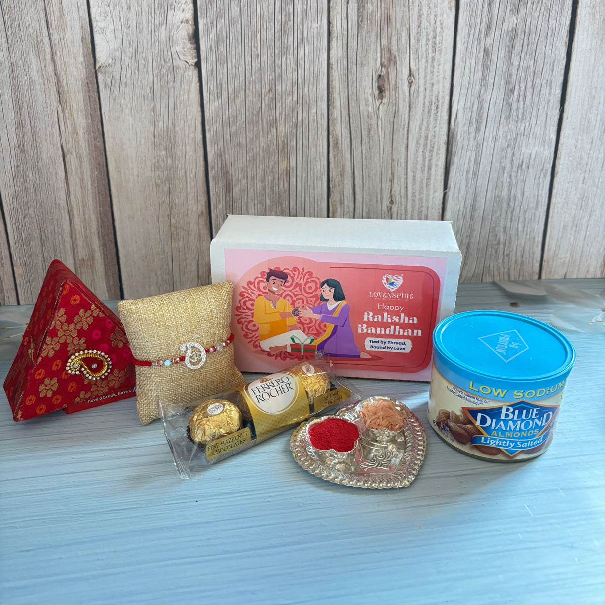Pure silver om rakhi gift hamper featuring a red and gold patterned triangular brocade gift box with paisley clasp