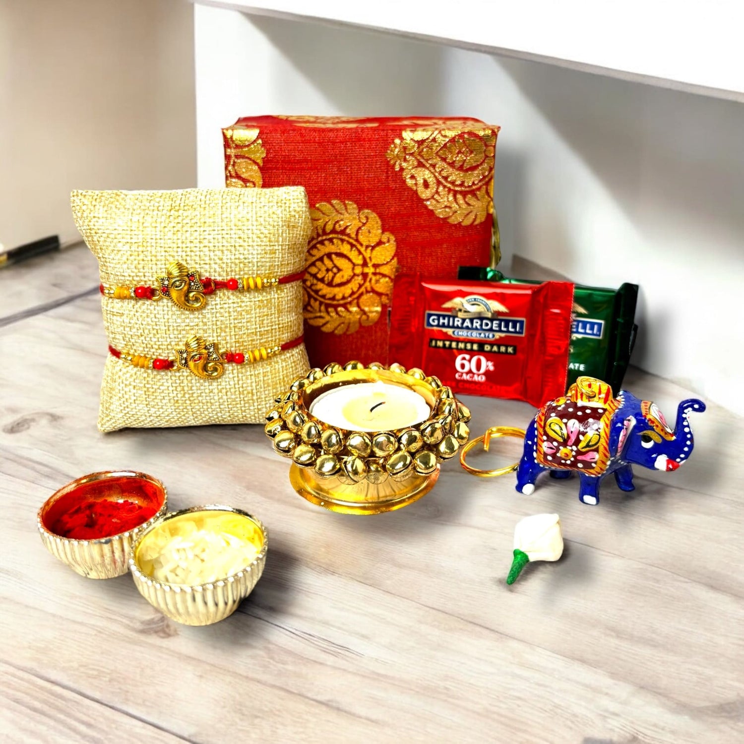 Rakhi gift arrangement with Ganesha Rakhi, chocolates, candle holder, key chain, and gift box