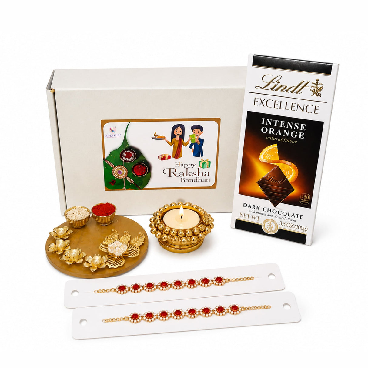 Gold-colored decorative tray with intricate floral designs holding bowls of red and white powders in rakhi gift hamper set