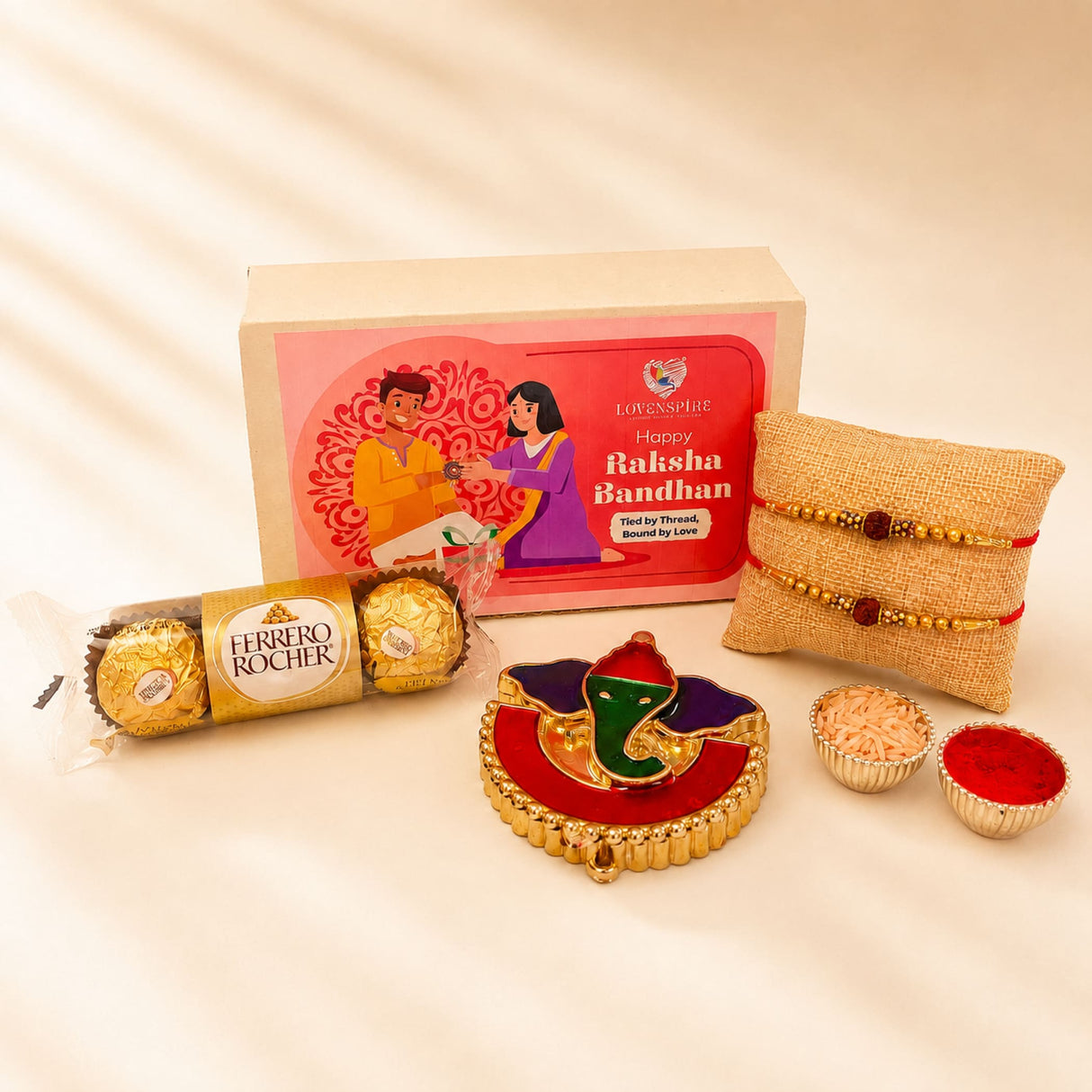Gold-colored ornate elephant-shaped handmade rakhi with red and green enamel accents in raksha bandhan gift hamper