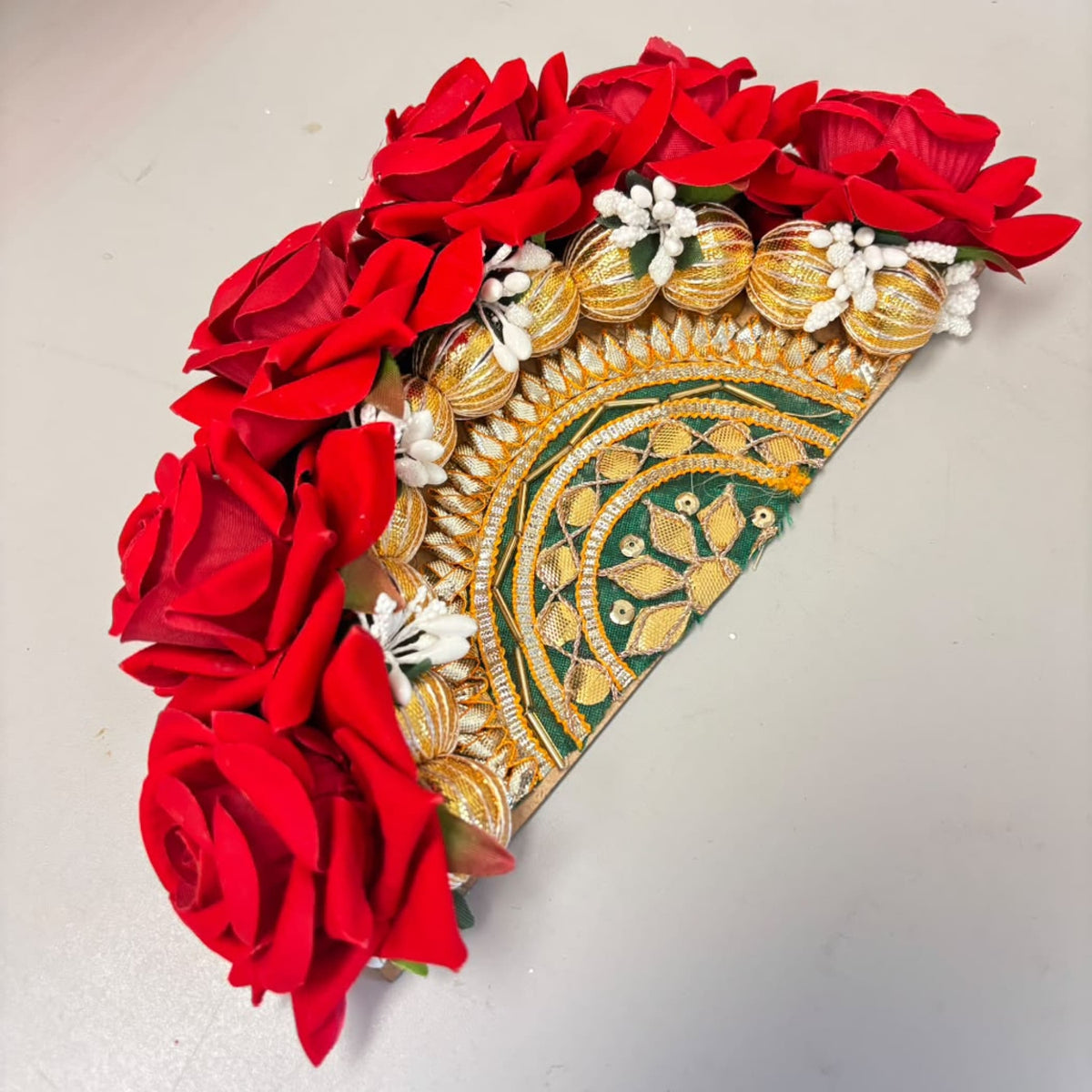 A vibrant red and gold floral decorative rose rangoli centrepiece with intricate embroidered patterns for diwali decor