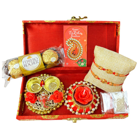 Raksha Bandhan gift box featuring Rudraksha Rakhi, chocolates, candle holder, and accessories