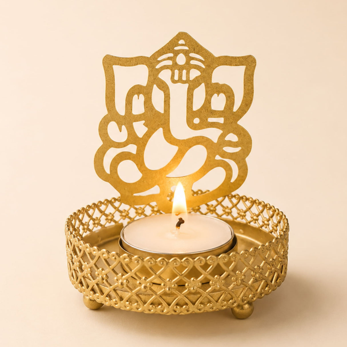 Golden metal ganesha-themed tea light candle holder with intricate lattice design and three small feet for diwali pooja decor