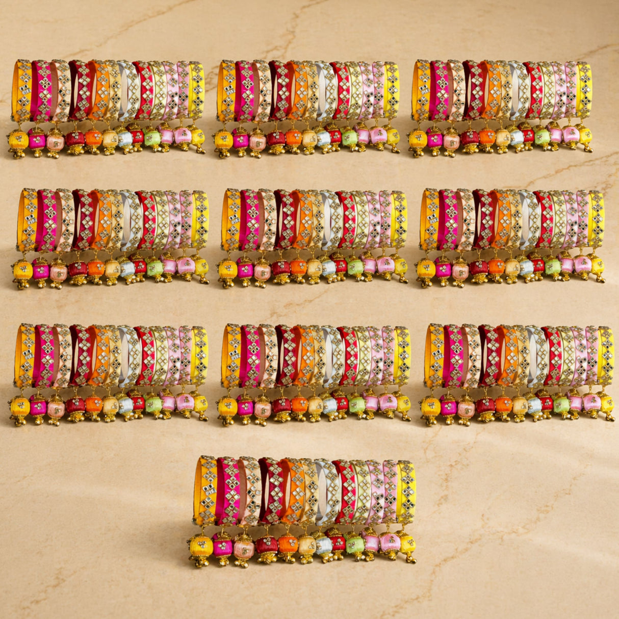 A set of vibrant silk thread bangles in pink orange yellow and white with kundan embellishments and colorful latkan beads