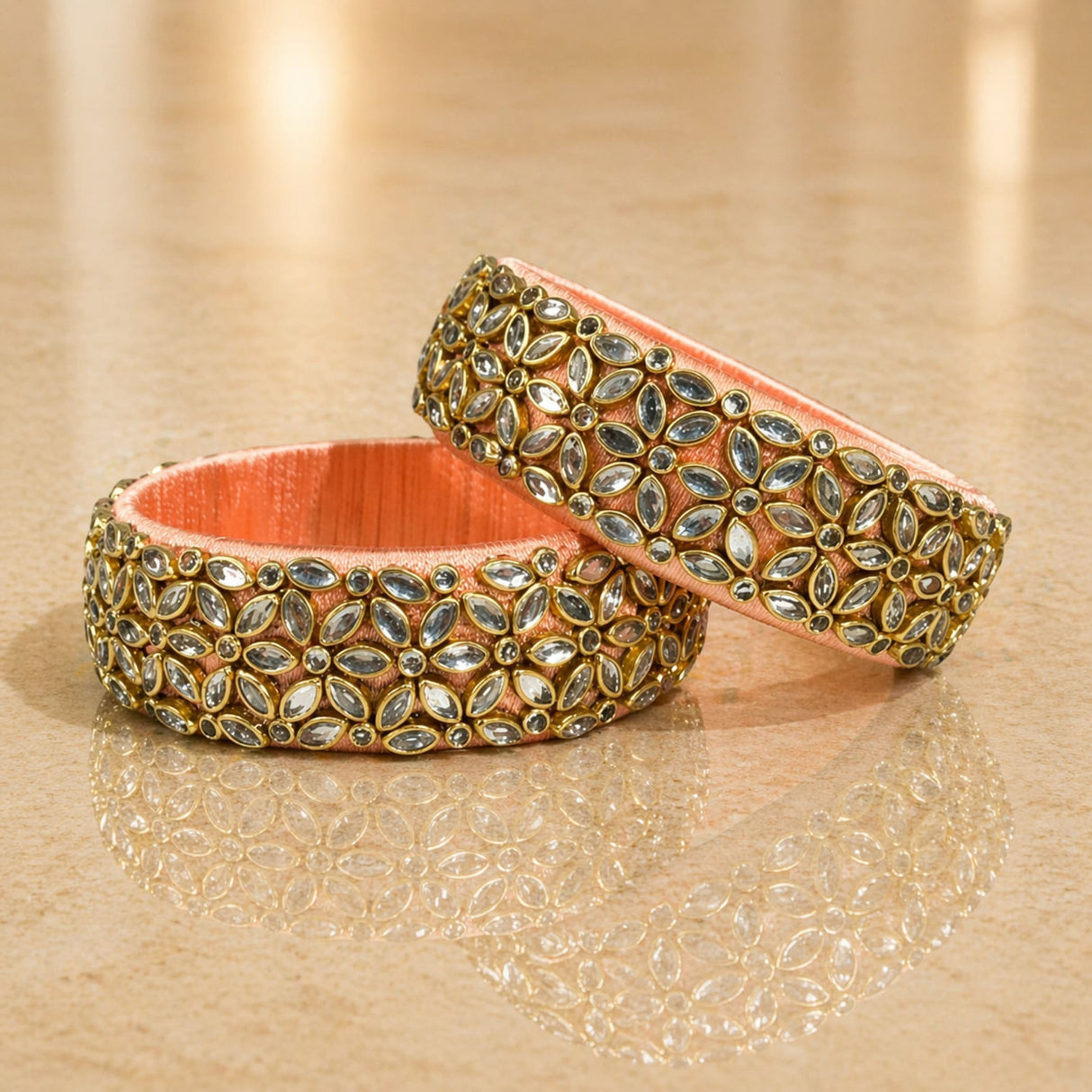 Ornate peach-colored Indian silk thread bangles with gold-toned settings and sparkling marquise-cut stones for women