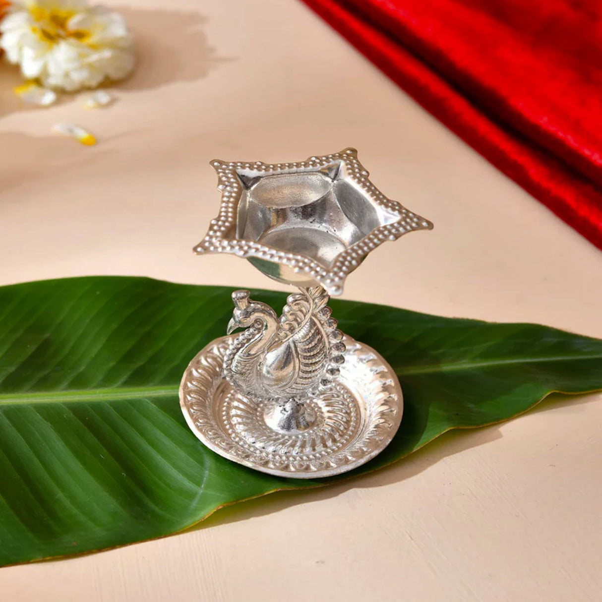 Silver plated peacock diya oil lamp with star shaped holder and intricate engravings for home pooja mandir