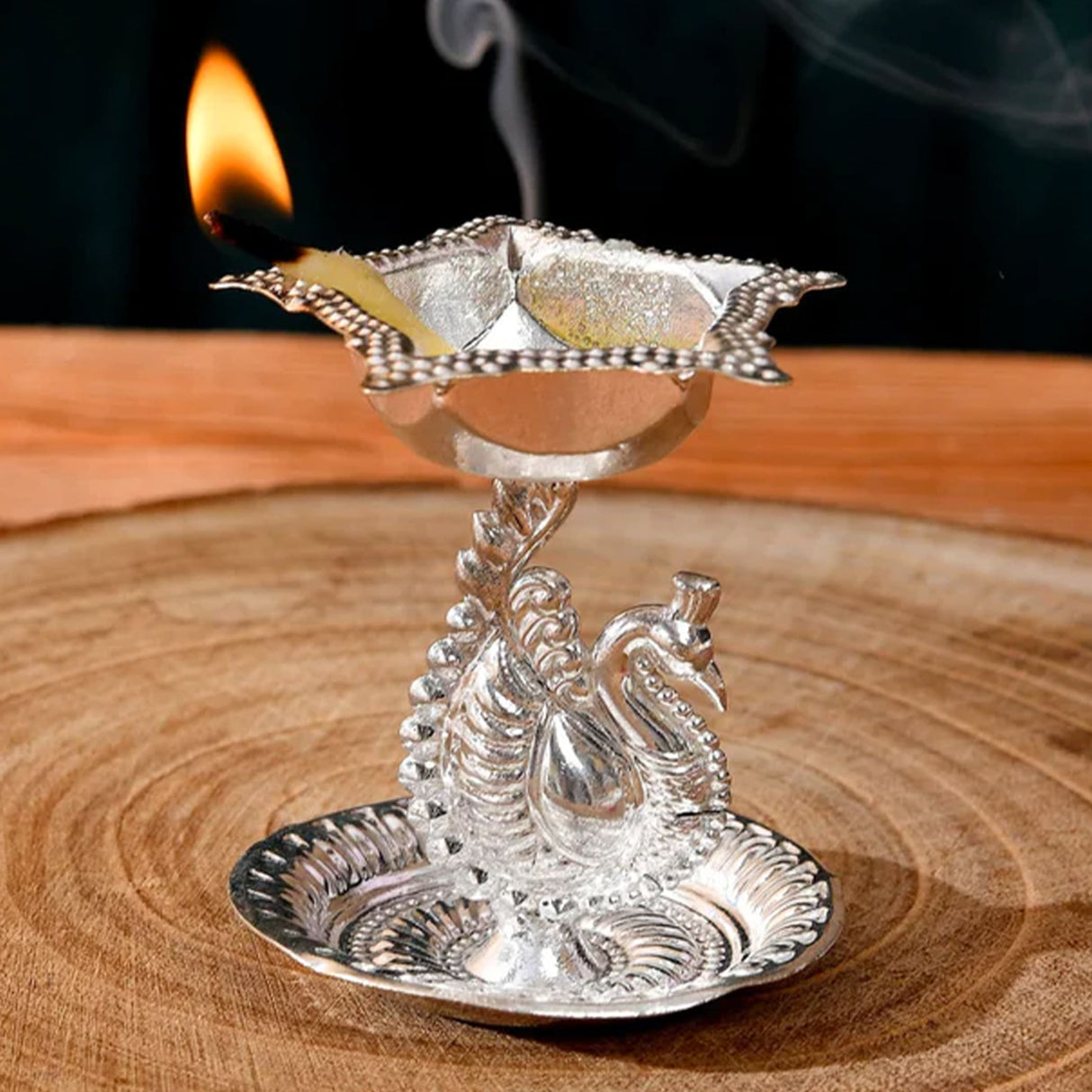 Silver plated peacock diya oil lamp with intricate engravings and flame for home pooja mandir and diwali decor