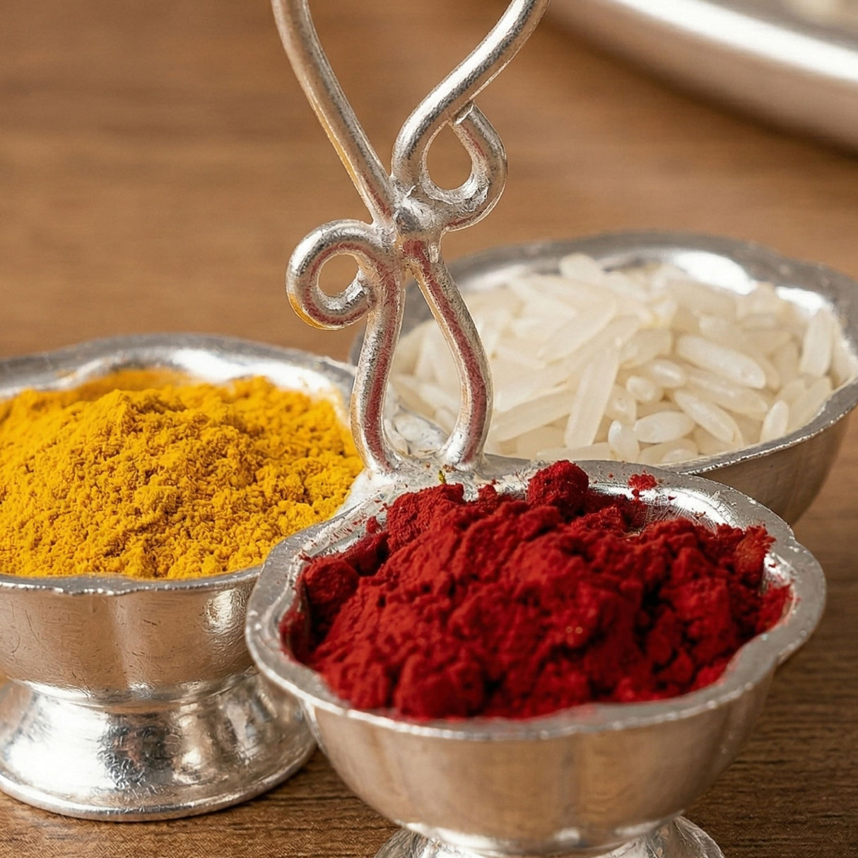 Silver plated haldi kumkum holder with three ornate compartments containing turmeric chili powder and rice for puja use