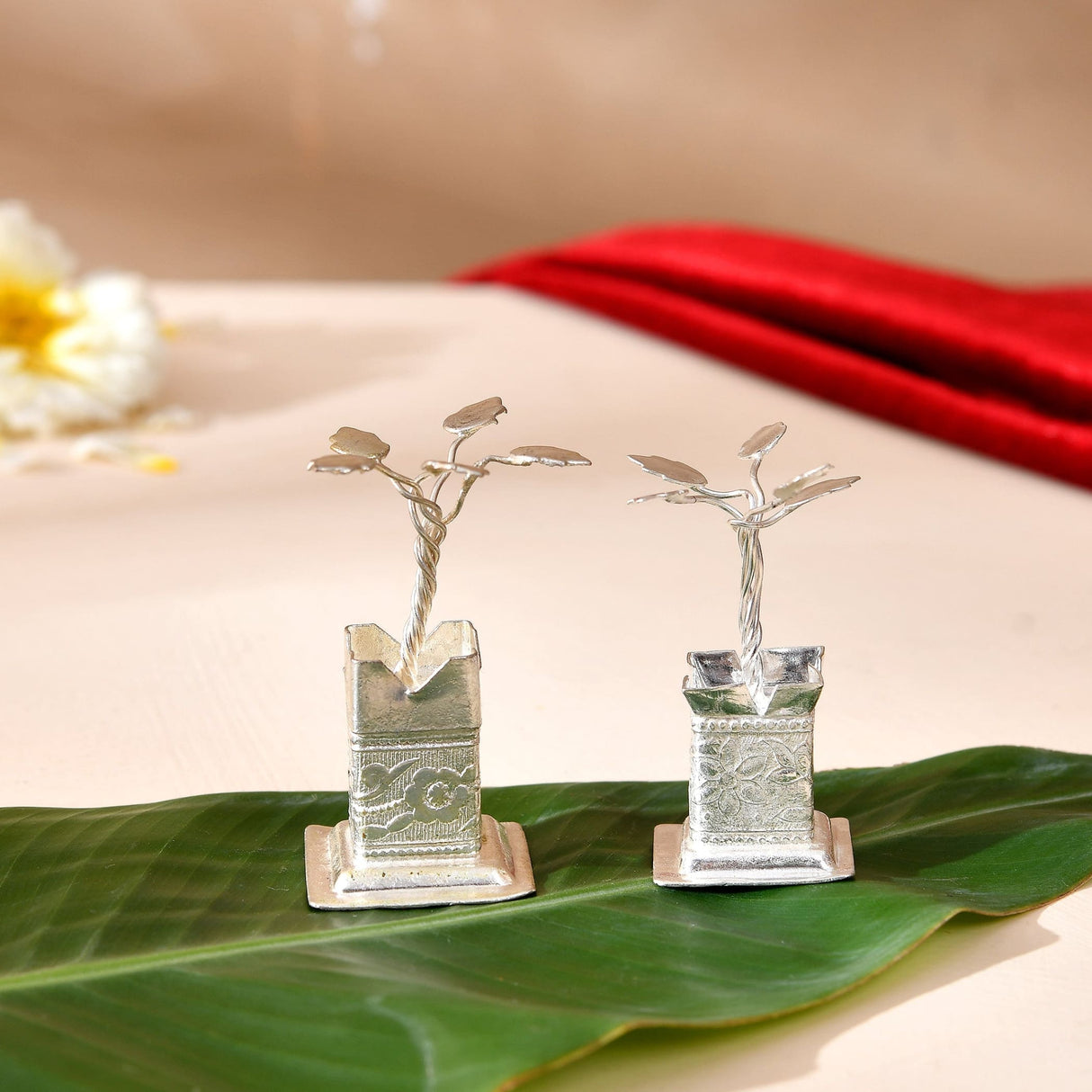Silver plated tulsi plant figurines with intricate engraved bases and twisted wire stems for home pooja mandir decor