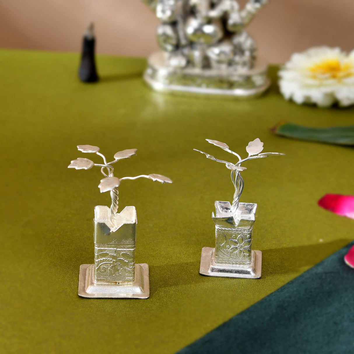 Silver plated tulsi plant figurines with intricate engraved bases and delicate leafy branches for pooja decor